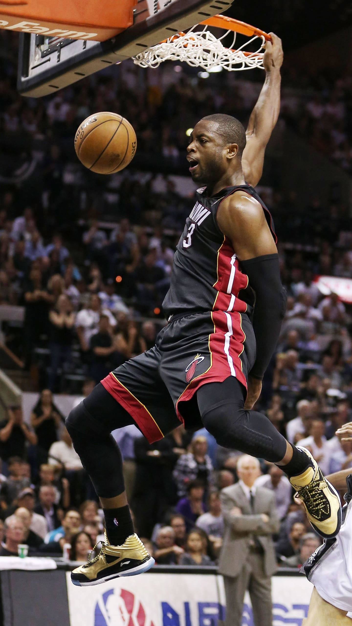 NBA 桌布 壁紙 — 一位身穿黑紅色球衣的籃球運動員在擠滿觀眾的體育館比賽中，專注地灌籃。