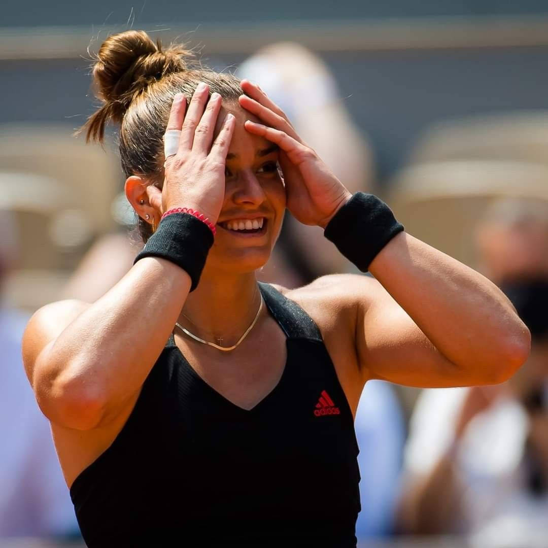 網球 桌布 壁紙 — 一位身穿黑色Adidas裝備的快樂女網球選手在陽光明媚的比賽中雙手放在頭上大笑。