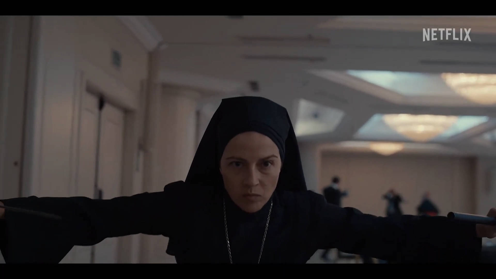 Film 桌布 壁紙 — 一位身穿黑色修女服的修女站在燈光昏暗的走廊中，專注地握著兩根警棍。