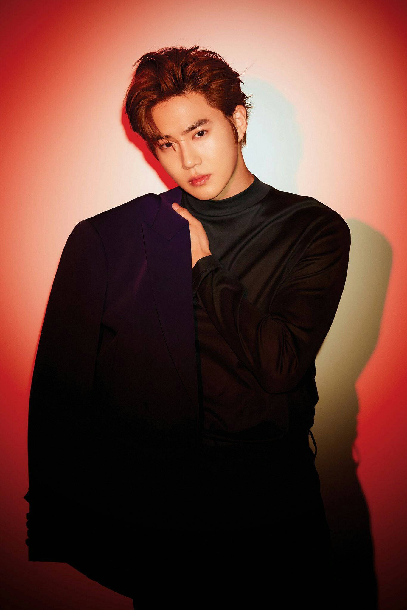 EXO 桌布 壁紙 — 一位身穿黑色服裝的年輕男子在紅色和橙色漸變的攝影棚背景前自信地擺姿勢，燈光效果戲劇化。