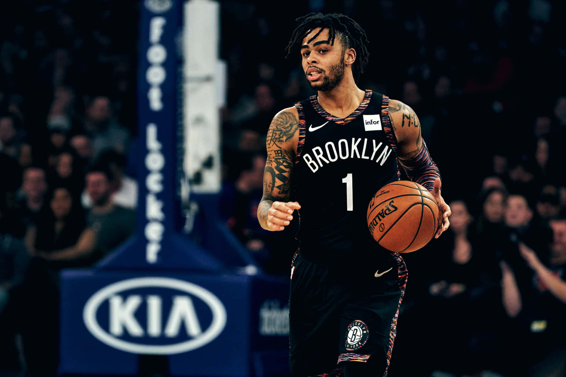 Brooklyn Nets 桌布 壁紙 — 一位身穿黑色球衣的布魯克林籃網籃球運動員在場館燈光下運球，背景是模糊的觀眾。