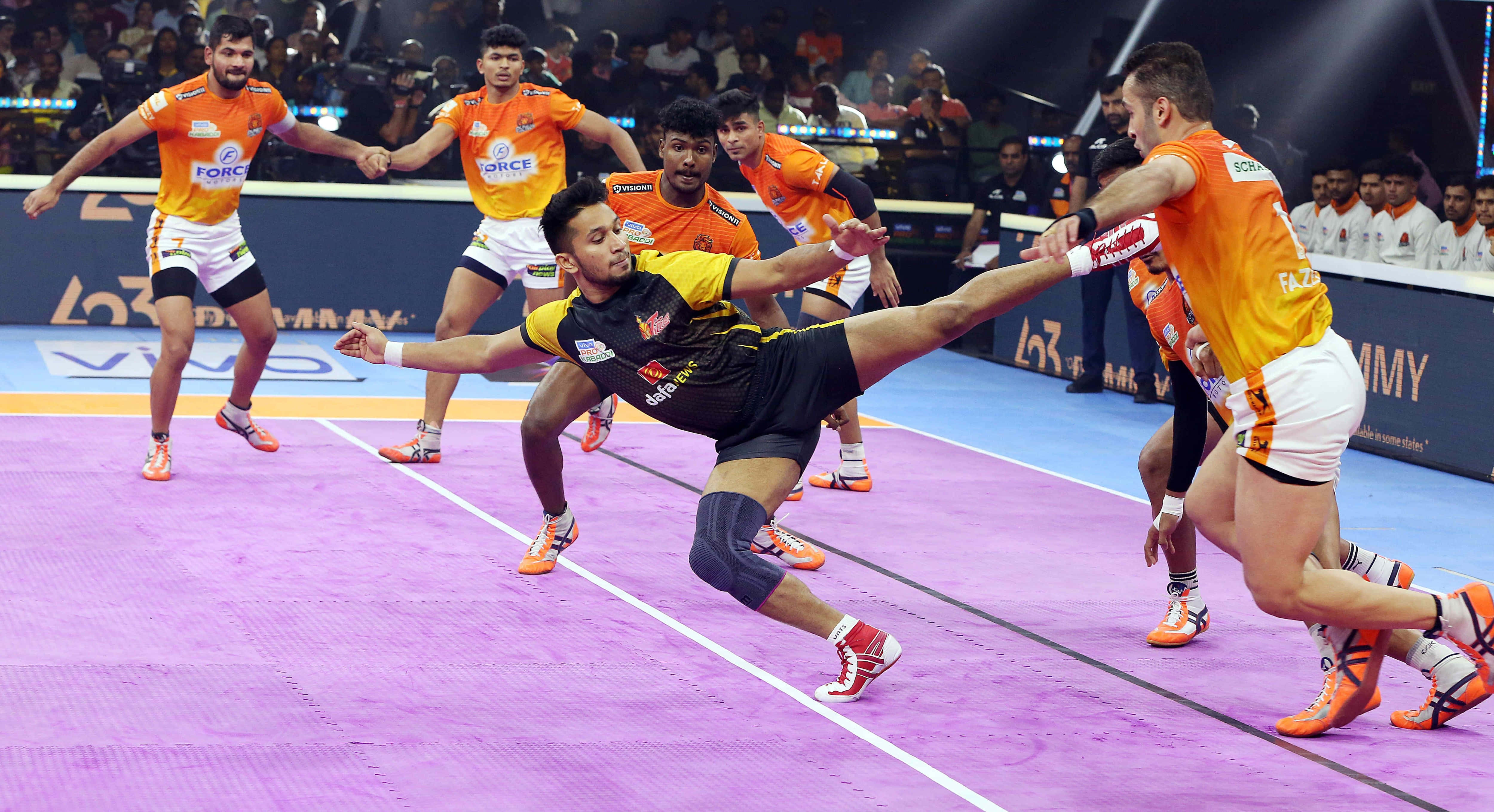 Kabaddi 桌布 壁紙 — 一位身穿黑色的動態板網球選手低身撲救回擊，而身穿橙色的對手在充滿活力的紫色場地上緊張地觀看。