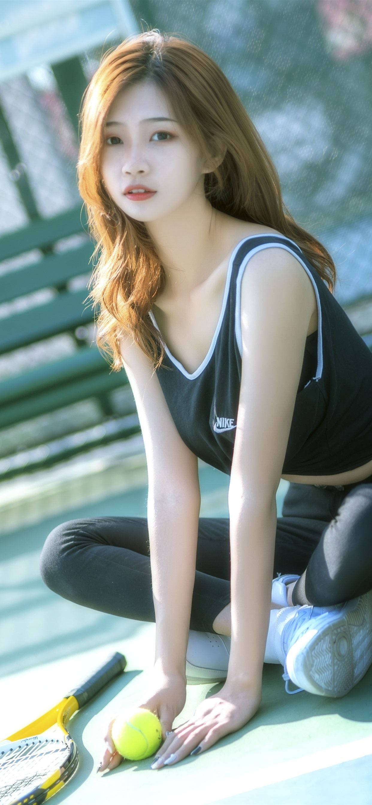 nike girl 桌布 壁紙 — 一位身穿黑色背心的年輕女子跪在網球場上，手持黃色球，旁邊放著球拍。