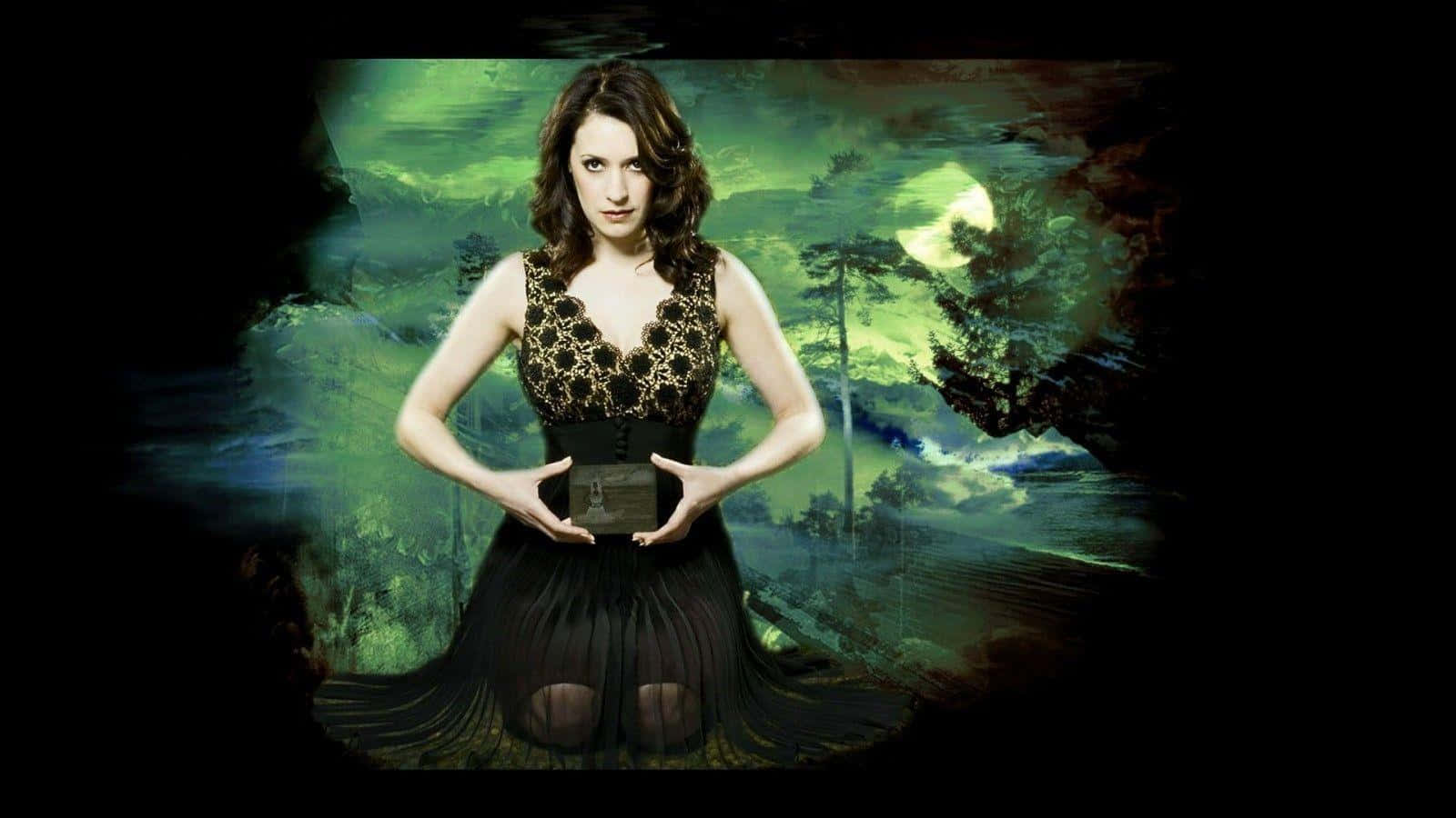 paget brewster 桌布 壁紙 — 一位身穿黑色蕾絲裙的女子，在發光的綠色月光森林背景下拿著一個盒子。