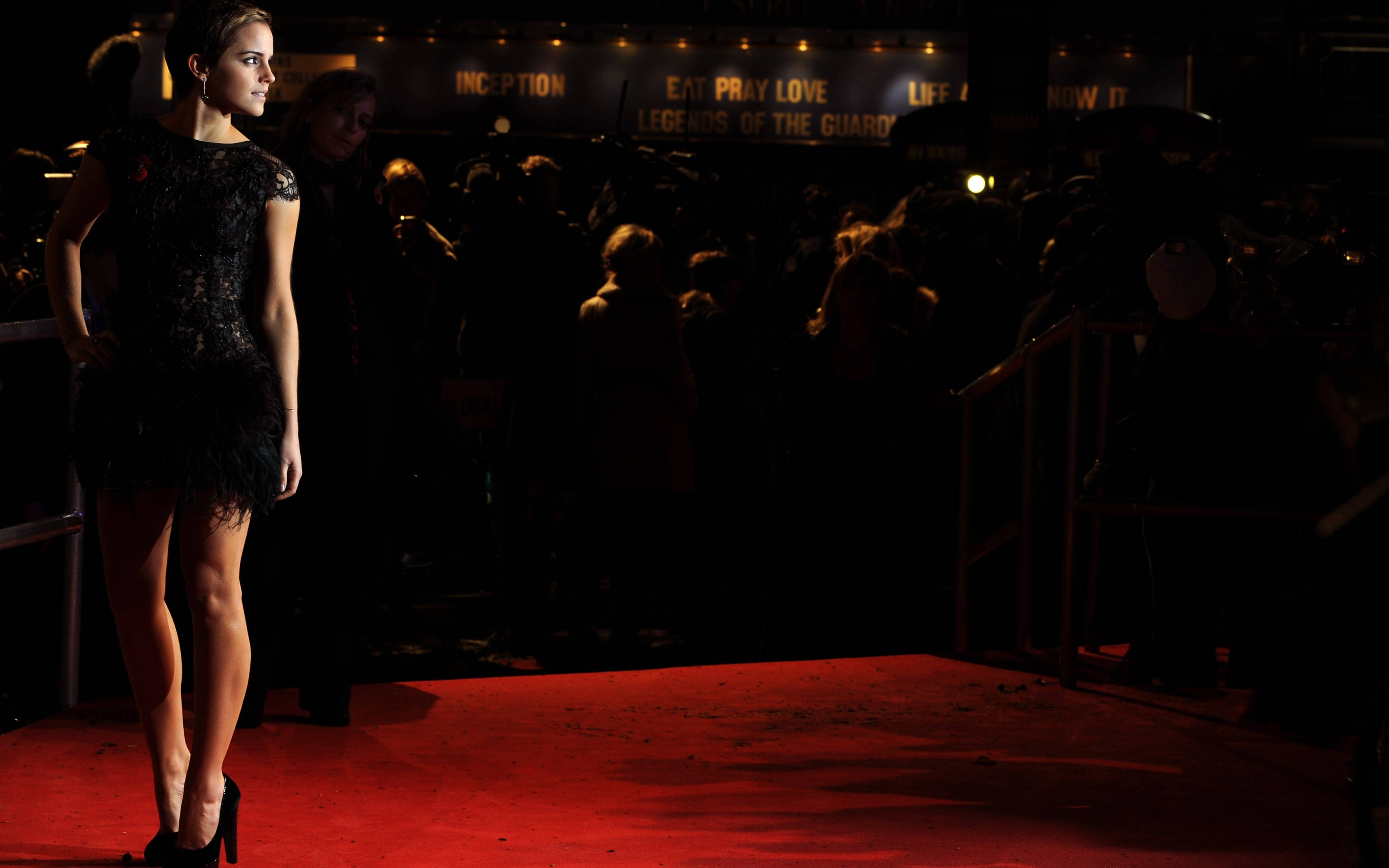 Red Carpet 桌布 壁紙 — 一位身穿黑色蕾絲連衣裙的女性在電影首映典禮上，於戲劇性燈光下優雅地站在紅地毯上。
