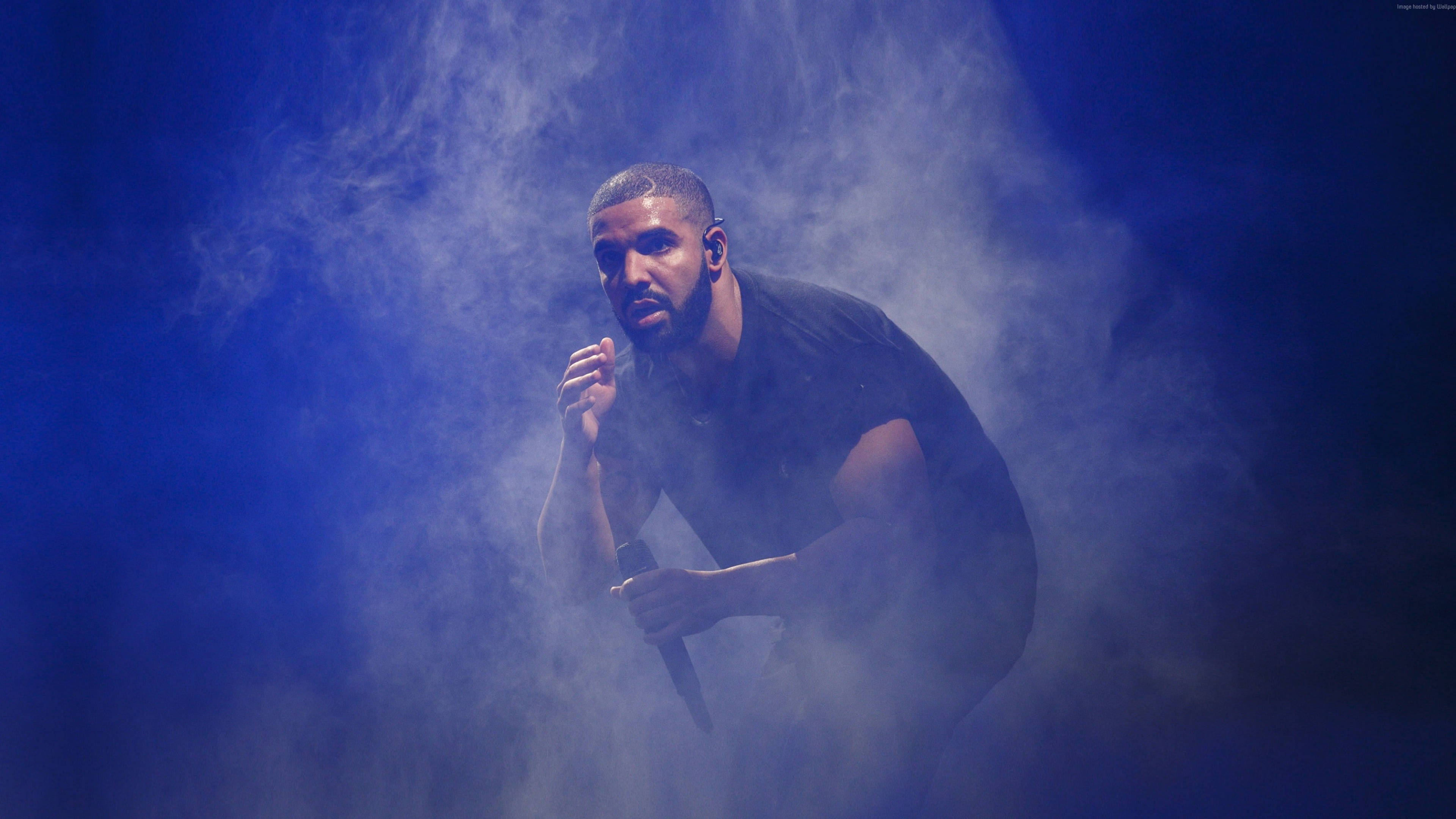 Drake 桌布 壁紙 — 一位身穿黑色襯衫的男性表演者在戲劇性的舞台燈光下，於旋轉的藍色煙霧中握著麥克風。
