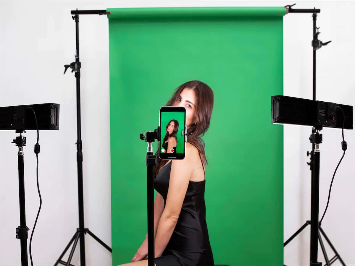 Modeling 桌布 壁紙 — 一位身穿黑色連衣裙的女性在設有綠幕和專業照明設備的攝影棚中擺姿勢。