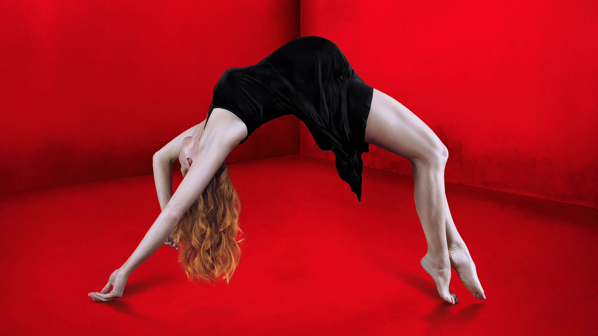American Horror Story 桌布 壁紙 — 一位身穿黑色連衣裙的女性在鮮紅色的工作室牆壁和地板上優雅地向後彎腰。