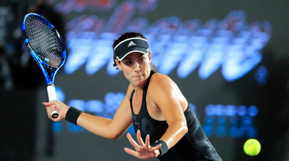 Athletic 桌布 壁紙 — 一位身穿黑色運動服的女網球手在明亮的體育場燈光下揮動藍色球拍擊打黃色網球。