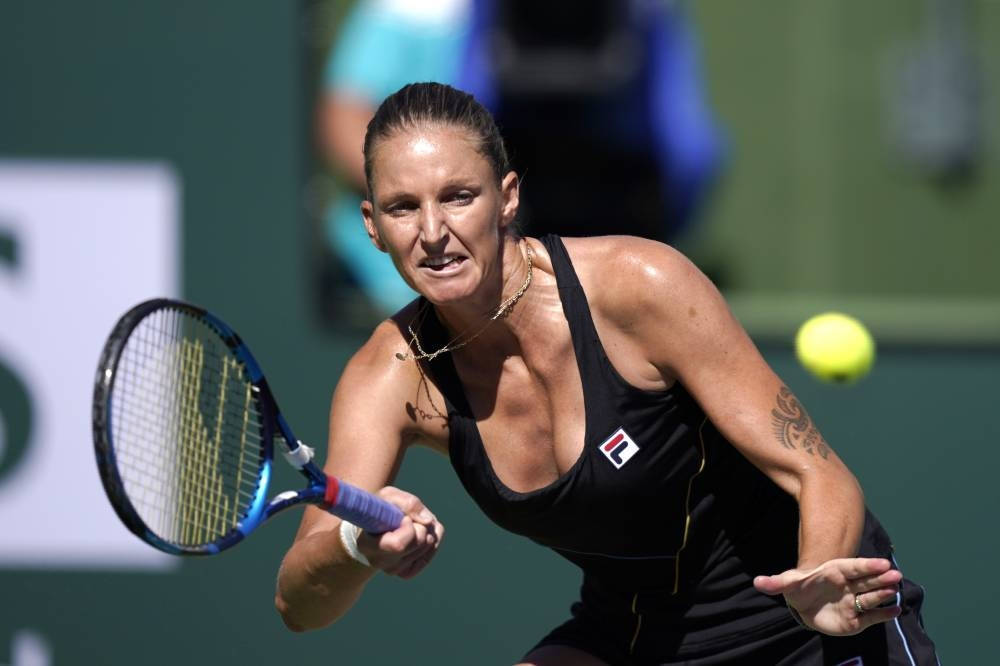 運動 桌布 壁紙 — 一位身穿黑色運動裝備的女網球選手在明亮的日光下，以高度專注力揮拍擊向黃色網球。