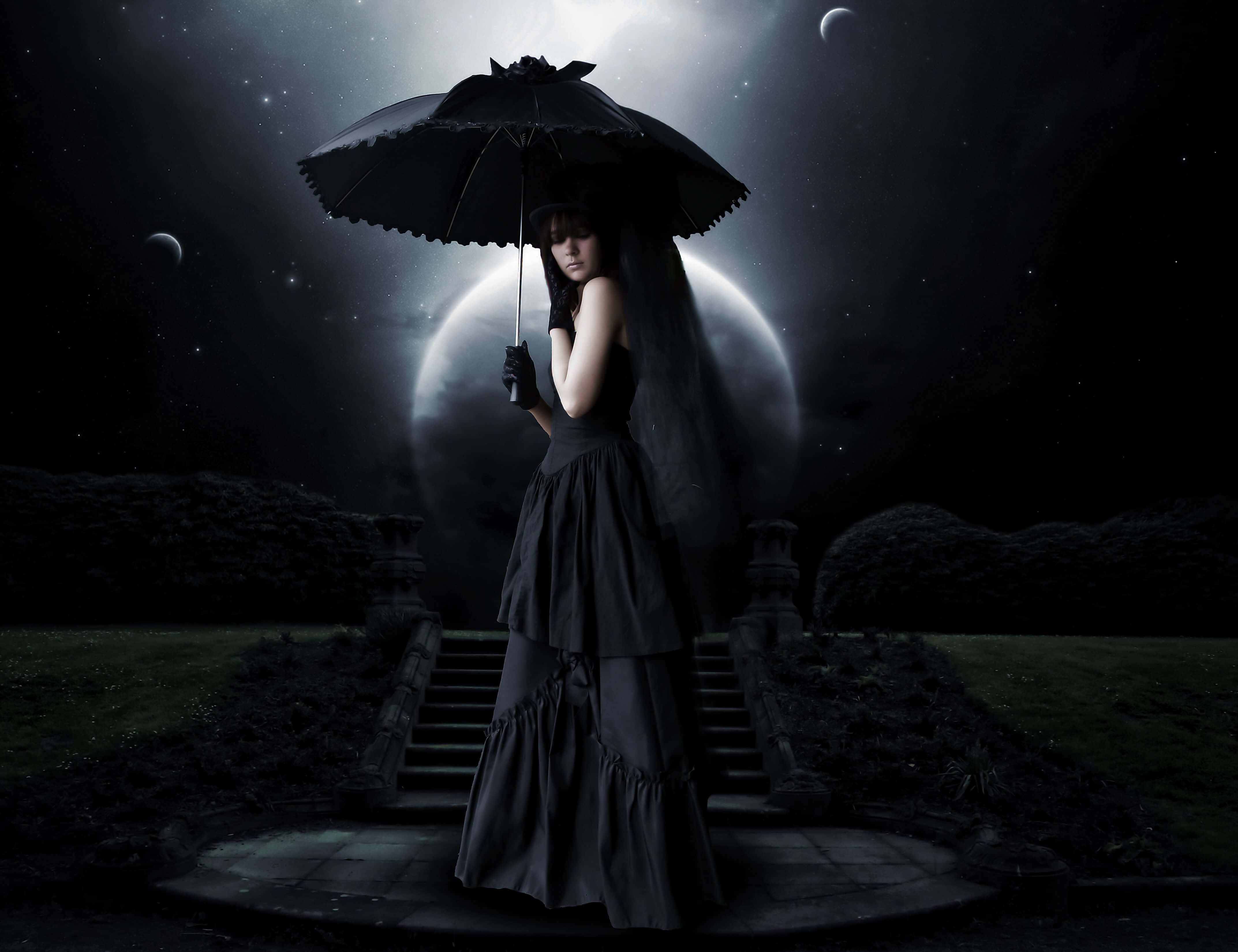 Dark Gothic 桌布 壁紙 — 一位身穿黑色長裙的女性在黑暗、星光燦爛的夜晚花園中，在發光的月亮下撐著一把黑色雨傘。