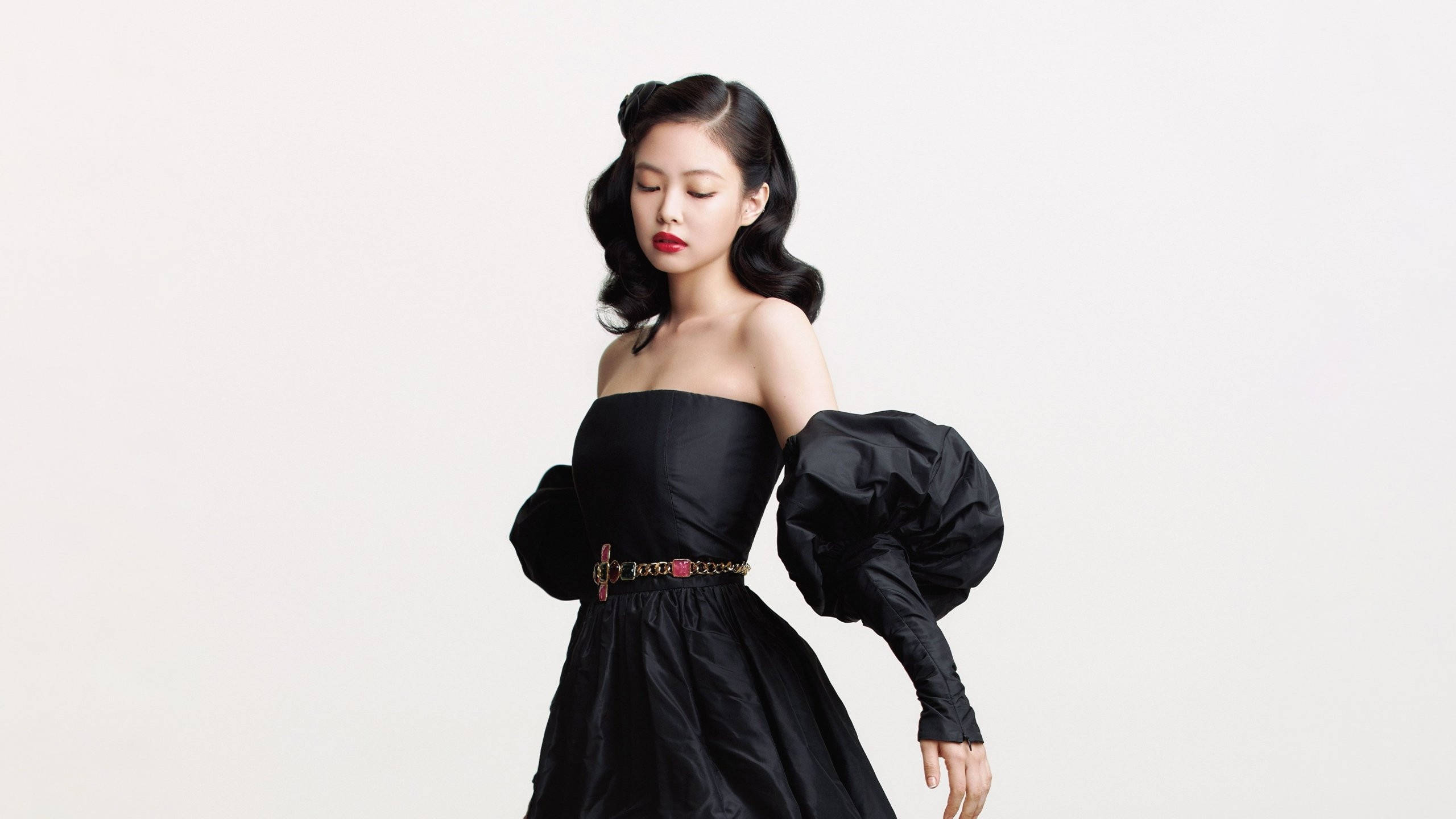BLACKPINK 桌布 壁紙 — 一位身穿黑色露肩泡泡袖連衣裙和金色腰帶的女性在純白色背景前擺姿勢。