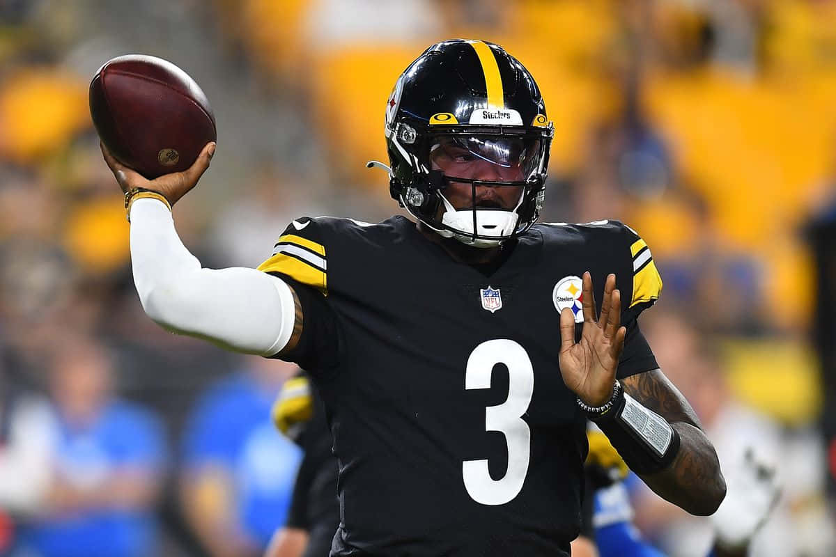 Dwayne Haskins 桌布 壁紙 — 一位身穿黑金球衣的匹茲堡鋼人四分衛在夜間比賽中準備擲出美式足球。