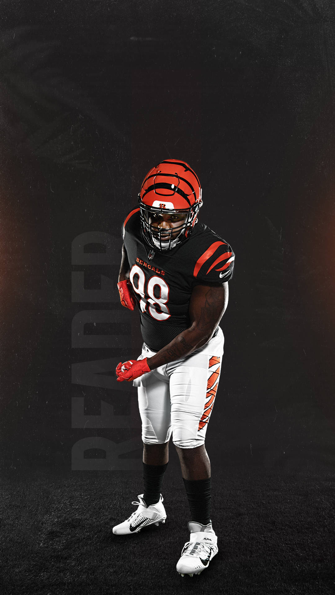 Bengals 桌布 壁紙 — 一位辛辛那提猛虎隊的美式足球員身穿黑色和橙色制服，在帶有微妙燈光點綴的深色紋理背景前擺好姿勢。