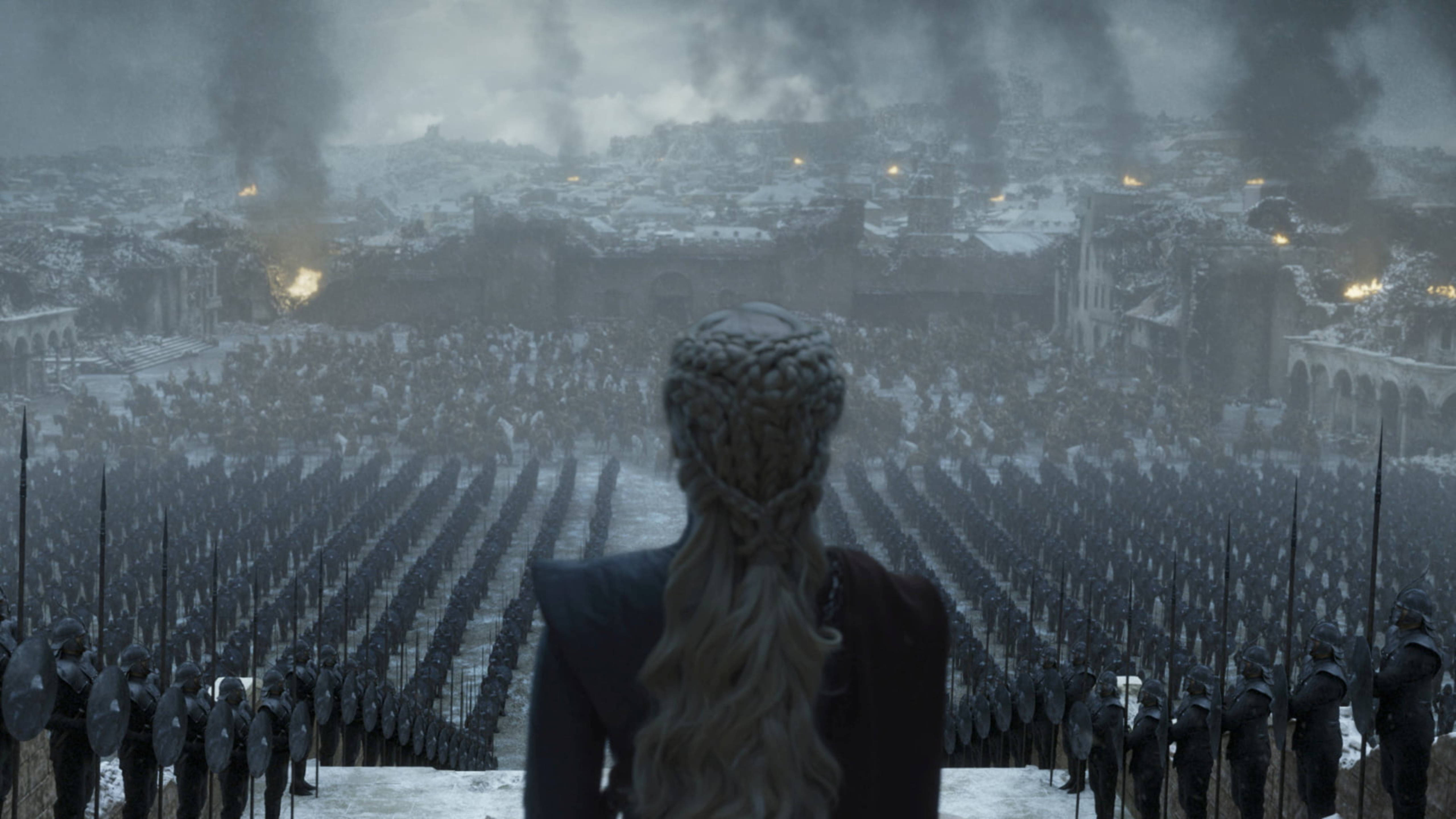 daenerys 桌布 壁紙 — 一位辮子女子站在白雪覆蓋的山丘上，俯瞰下方廣大的士兵軍隊和燃燒的城市。