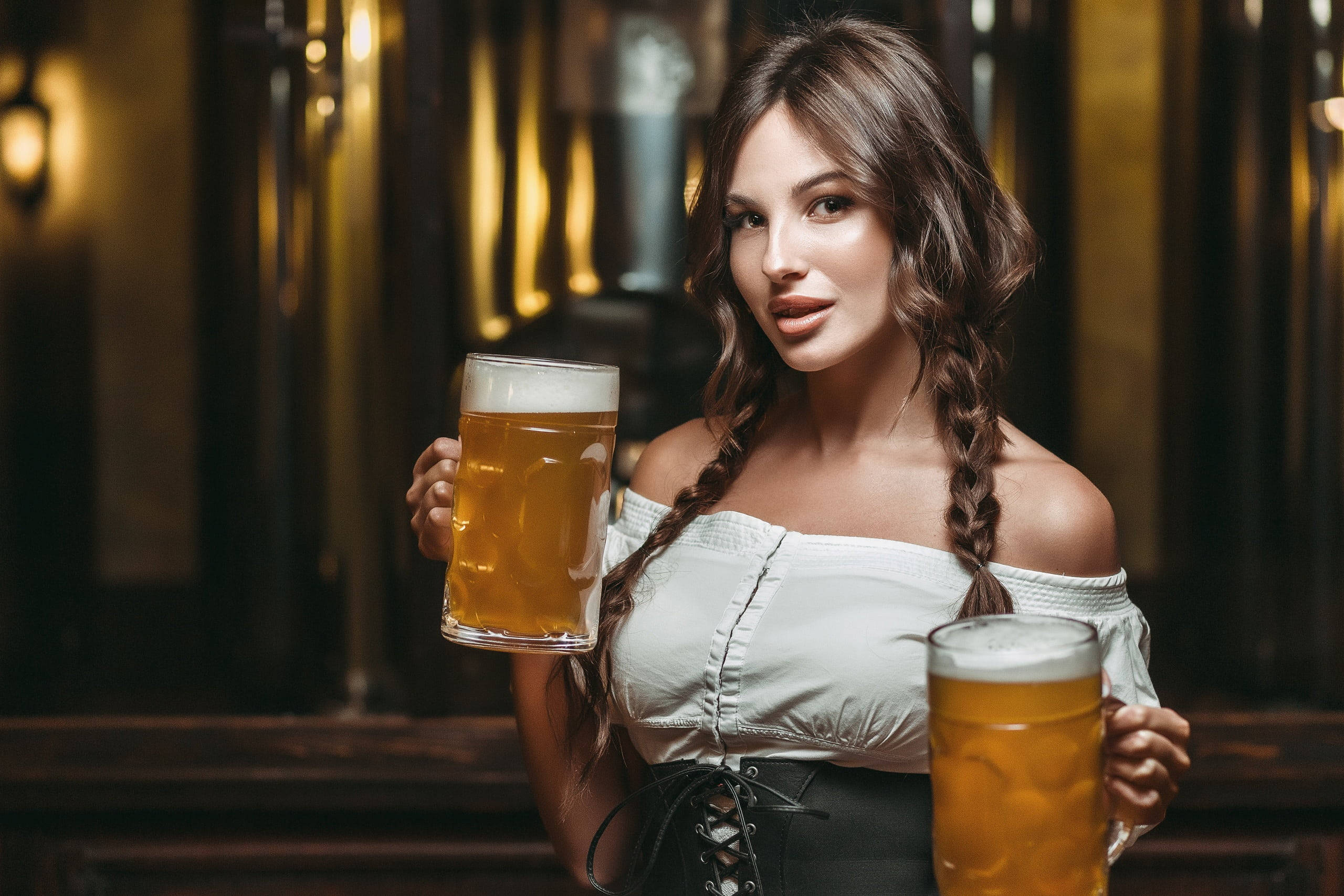 Beer 桌布 壁紙 — 一位辮子女性在溫暖燈光的釀酒廠中，身後有木桶，手持兩杯泡沫啤酒。