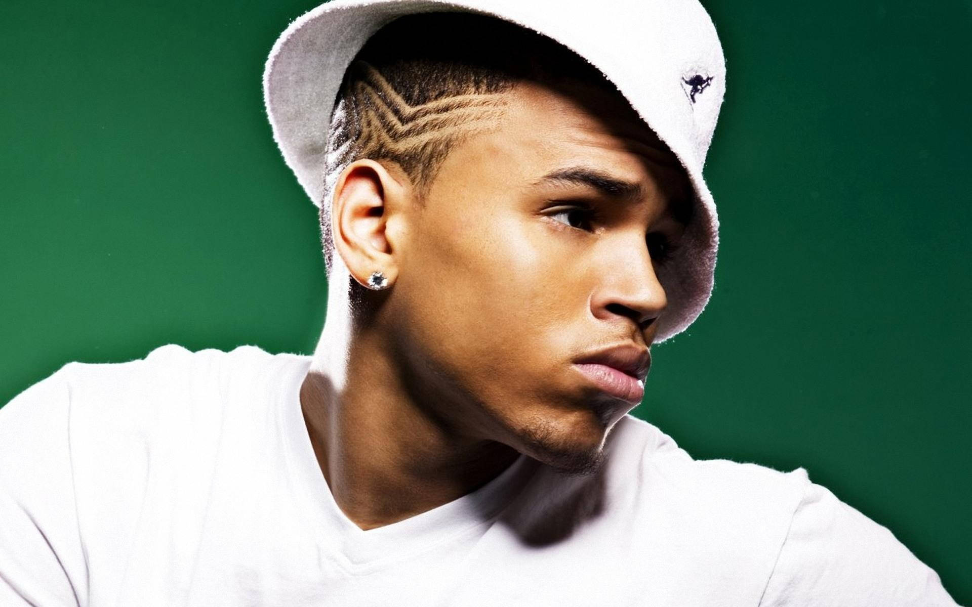 Chris Brown 桌布 壁紙 — 一位辮子頭髮、戴白色帽子的年輕男子，在純綠色背景下專注地凝視。