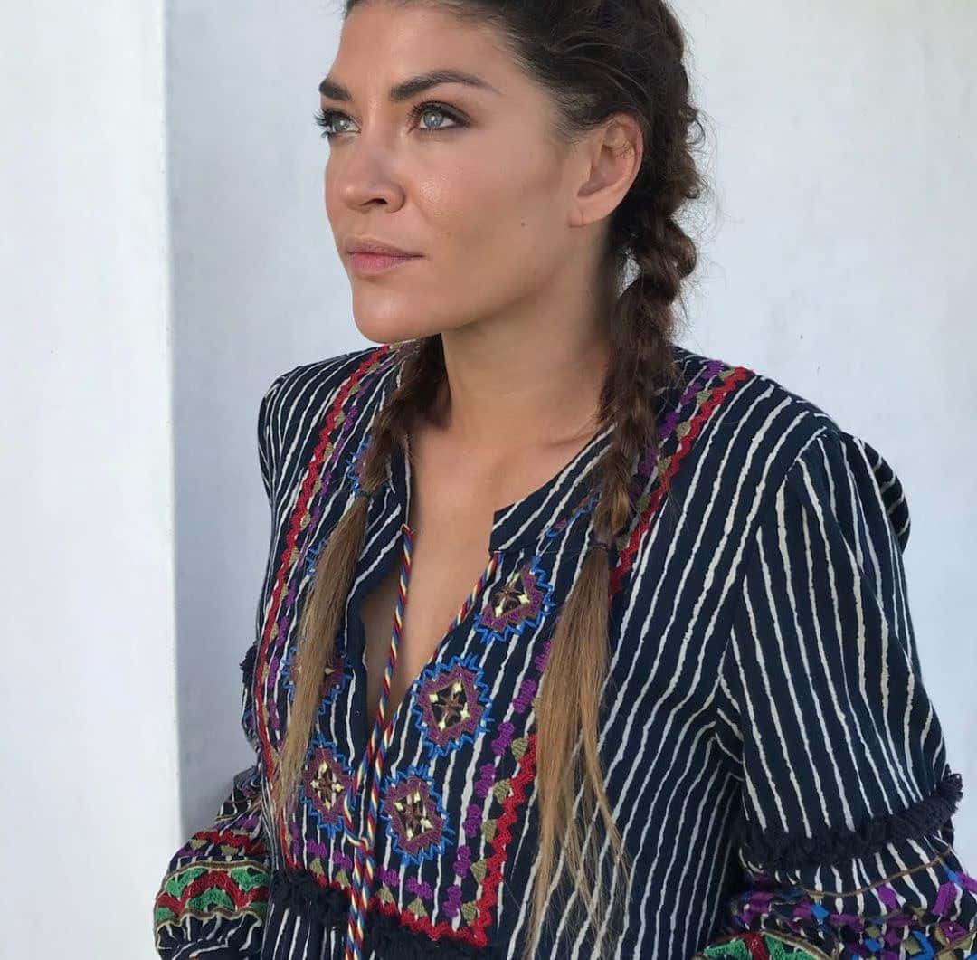 jessica szohr 桌布 壁紙 — 一位辮子髮型的女性穿著海軍藍條紋襯衫，上面有彩色刺繡星星圖案，背景是純白牆壁。