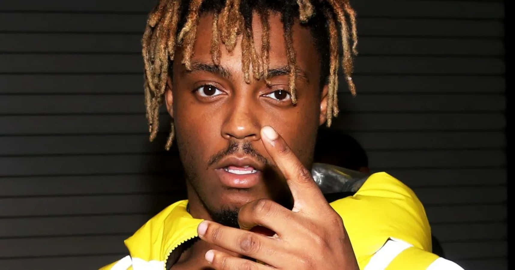 辮髮年輕男子身穿黃色外套指向相機。 — Juice Wrld 壁紙