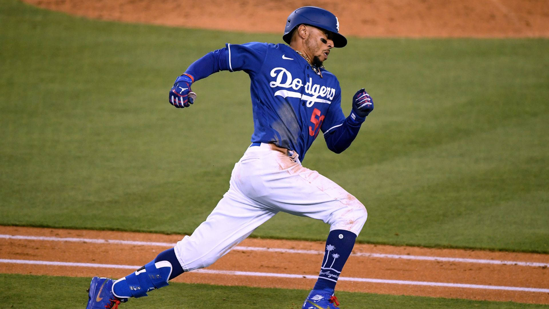Mookie Betts 桌布 壁紙 — 一位道奇隊棒球選手在夜間比賽中以動態動作沿著壘道衝刺。