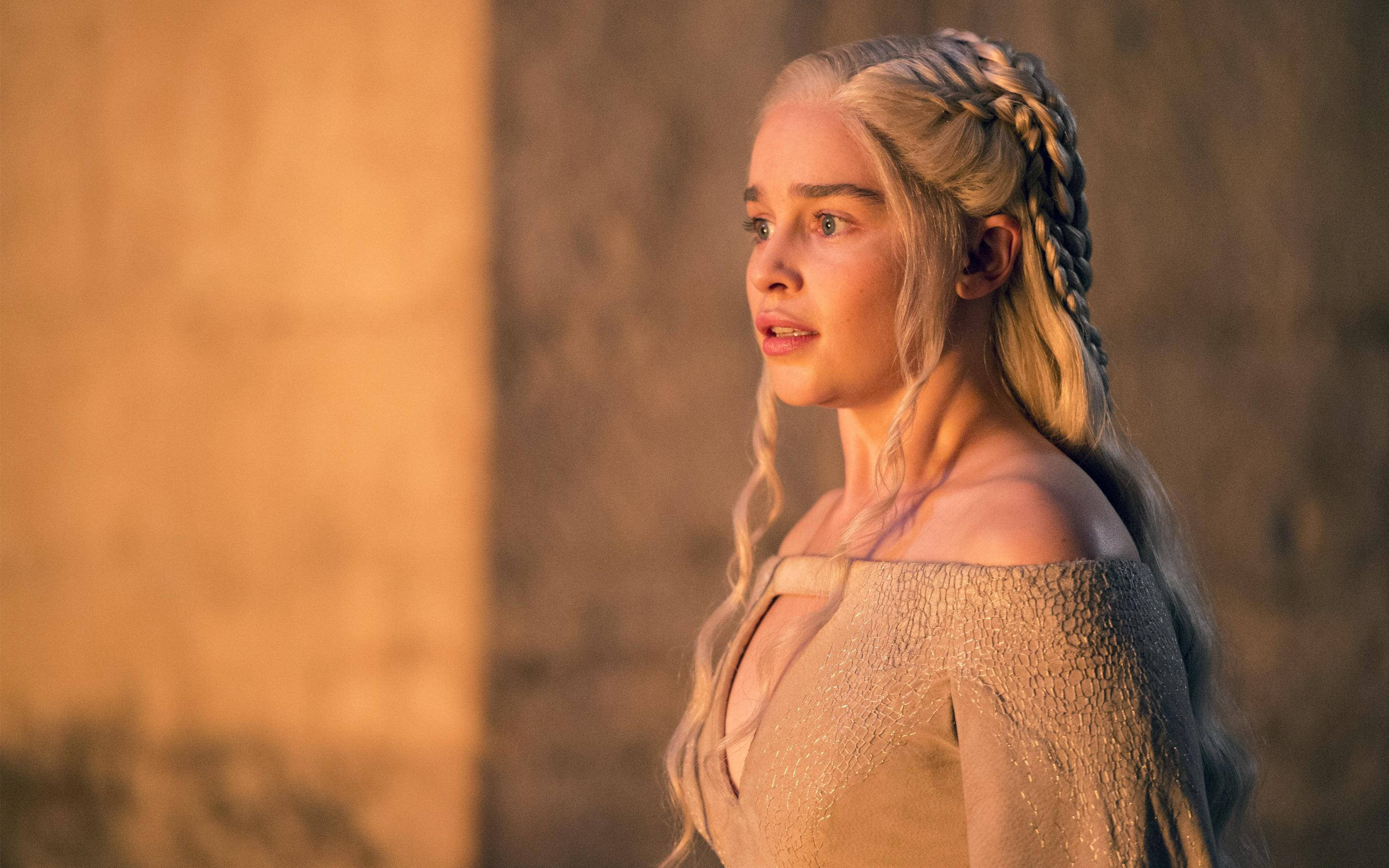 Emilia 桌布 壁紙 — 一位金色辮子女性在金色光線沐浴的溫暖紋理石牆前沉思凝視。