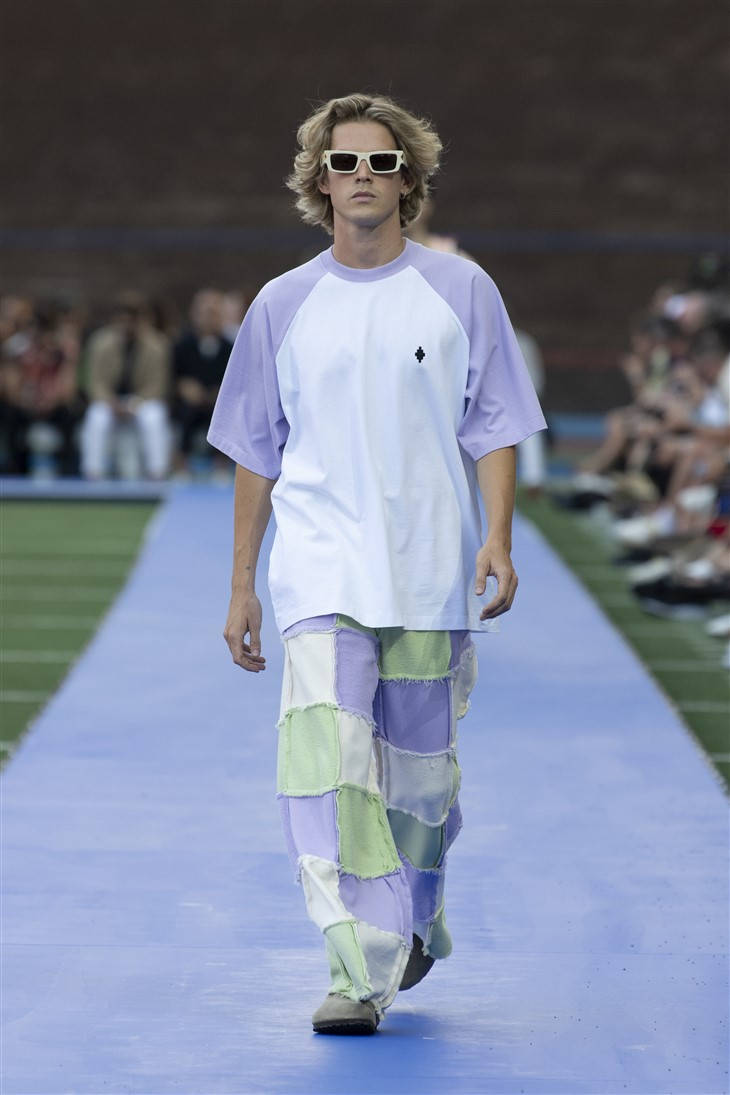 Fashion Model 桌布 壁紙 — 一位金髮、戴白色太陽眼鏡的模特兒自信地走在藍色T台上，身穿薰衣草和白色插肩袖T恤和拼布褲。