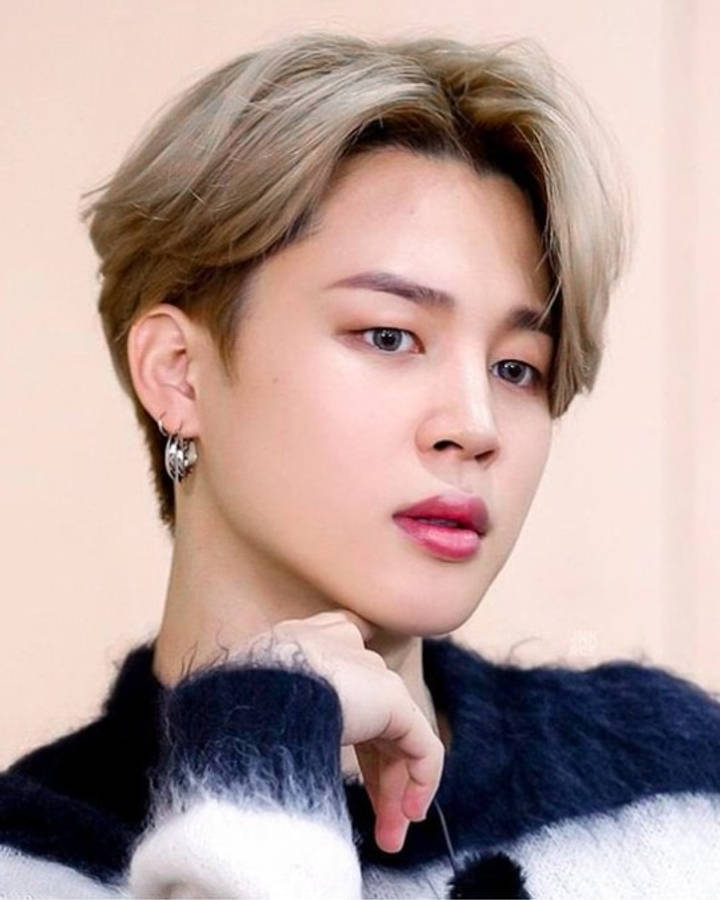 BTS 智旻 桌布 壁紙 — 一位金髮、戴著銀色耳環的年輕男子，身穿藍白相間的毛絨毛衣，手托著下巴。