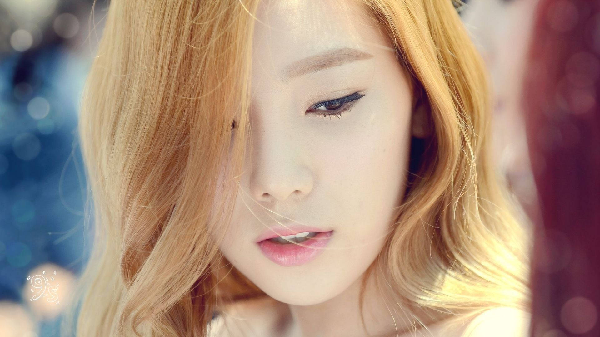 태연 桌布 壁紙 — 一位金髮、淡妝的年輕女性的特寫肖像，帶著溫柔的表情向下凝視。