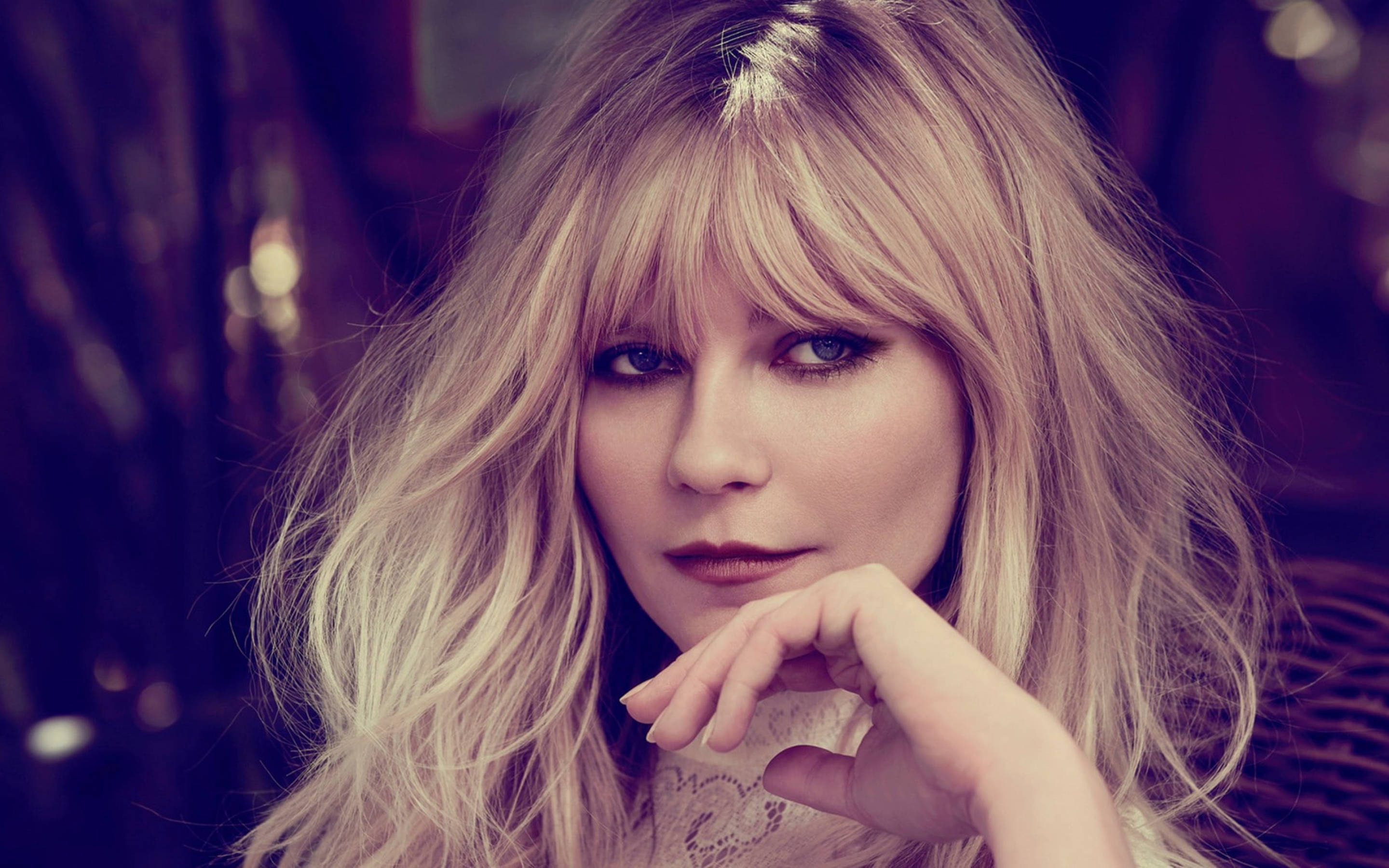 Kirsten Dunst 桌布 壁紙 — 一位金髮凌亂的女子，在柔和模糊的背景前，托腮凝視。