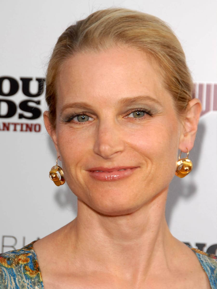 Celebrity 桌布 壁紙 — 一位金髮向後梳的女性戴著金色耳環，對著鏡頭溫柔微笑的特寫肖像。