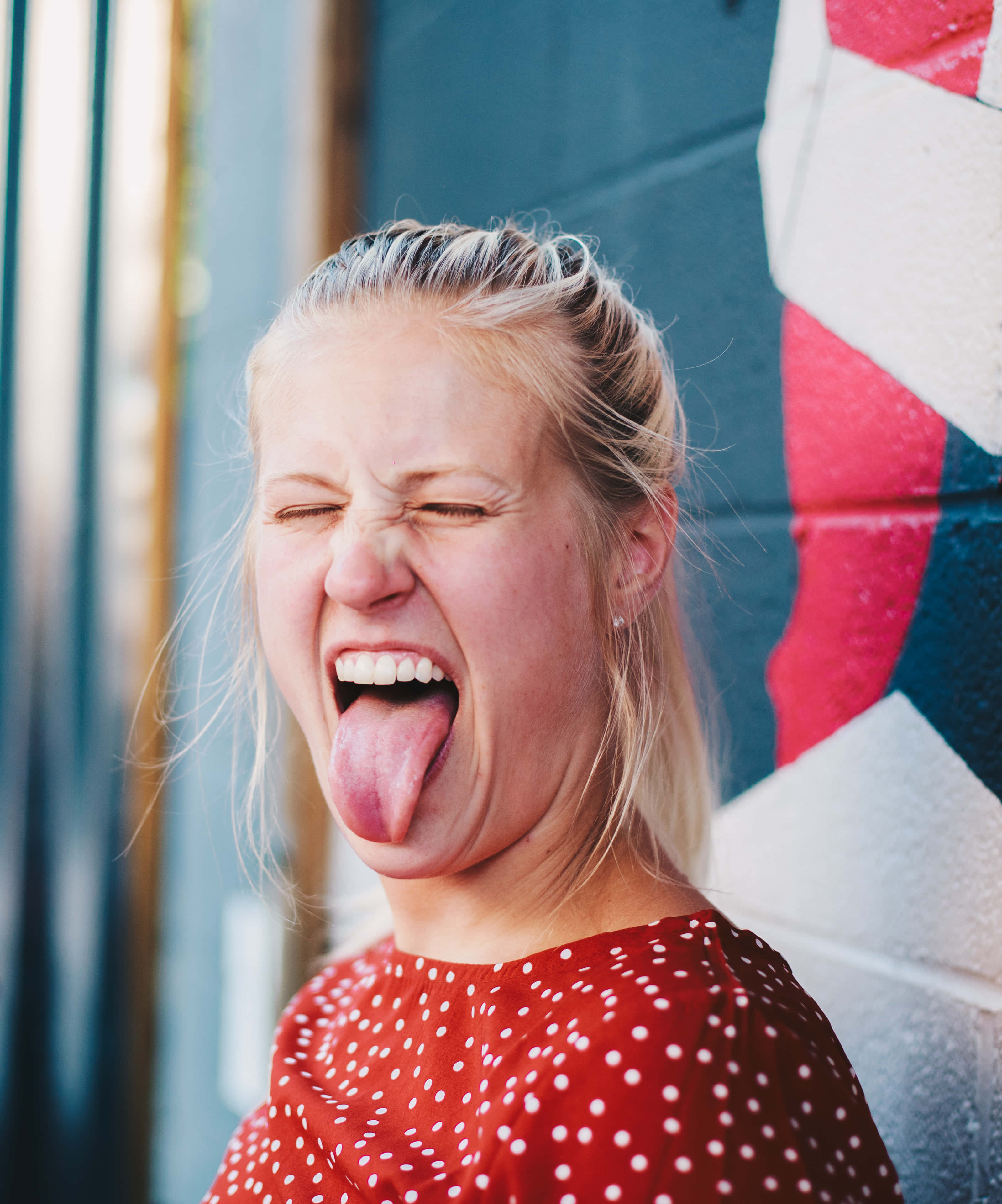 sticking tongue out 桌布 壁紙 — 一位金髮女子在色彩繽紛的塗鴉牆前大笑並伸出舌頭。