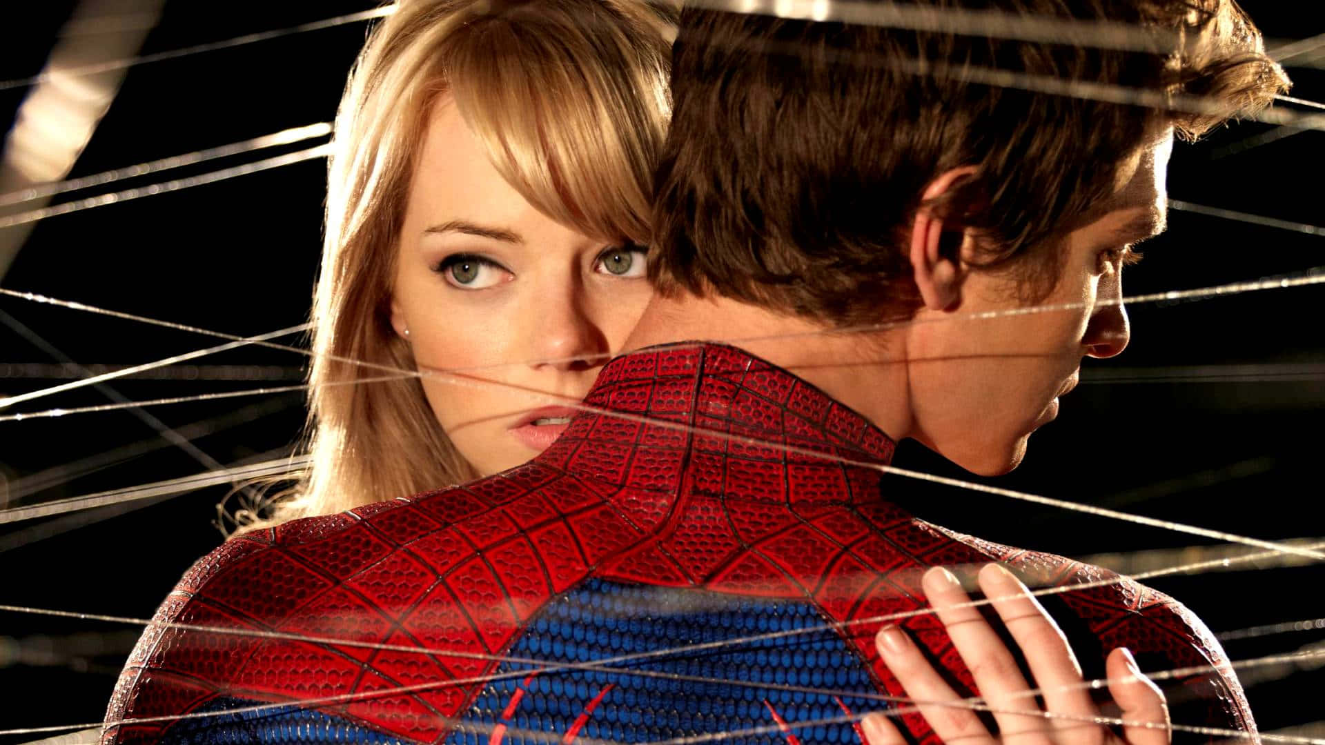 Gwen Stacy 桌布 壁紙 — 一位金髮女子在蜘蛛網交錯的黑暗背景前，專注地越過蜘蛛人的肩膀凝視。