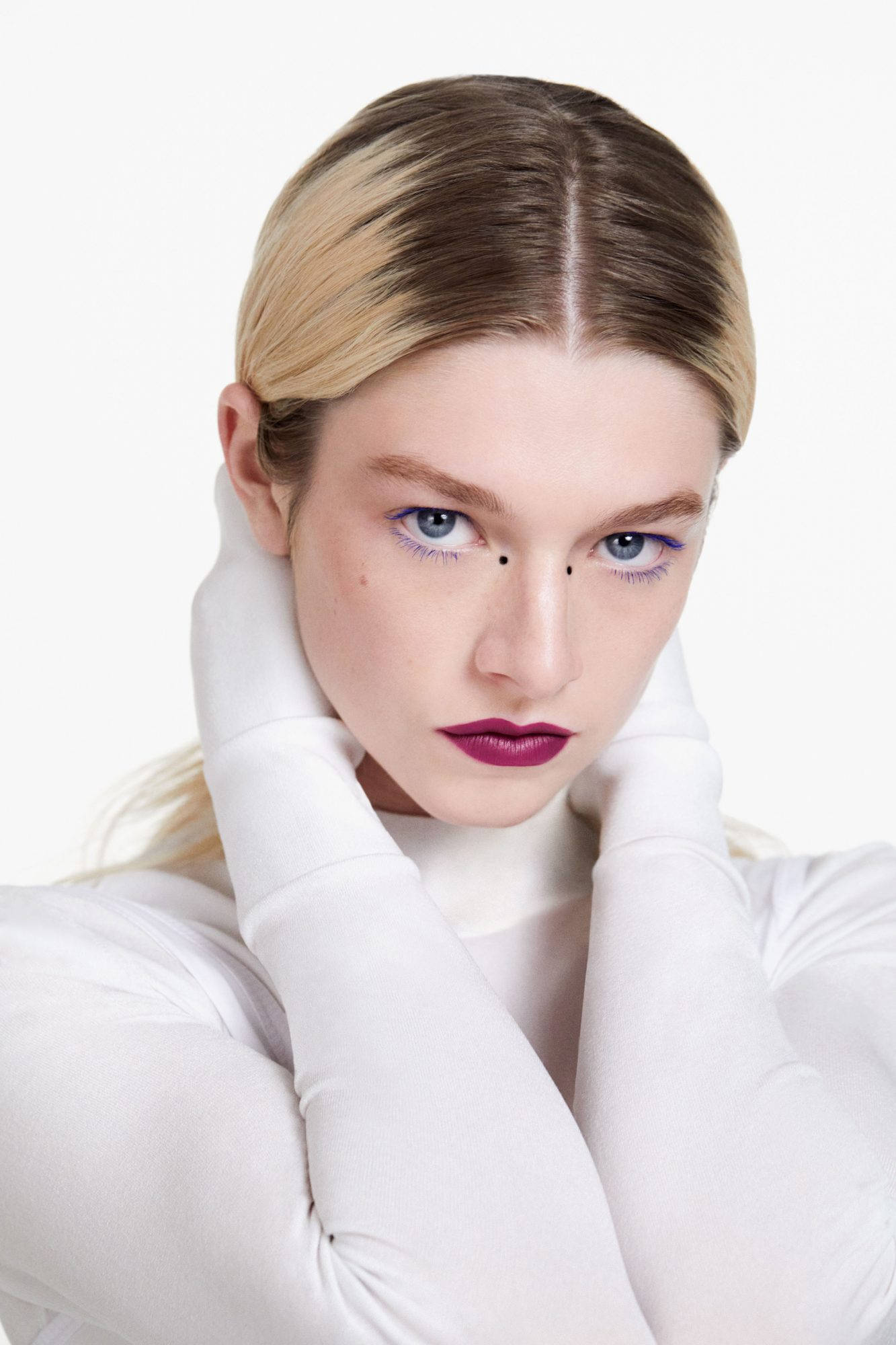 Hunter Schafer 桌布 壁紙 — 一位金髮女子塗著大膽的紫色唇膏，戴著白色手套，在純白背景前凝視著。