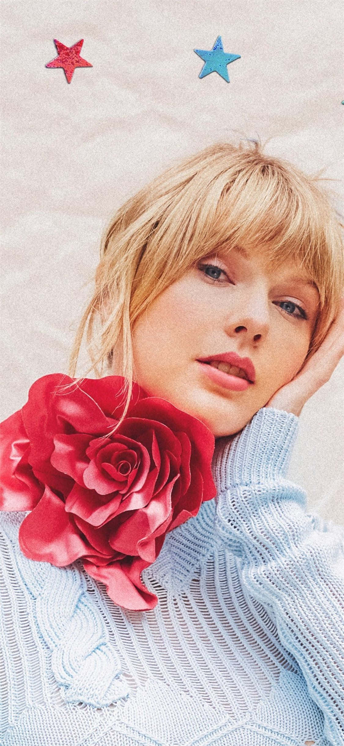 Taylor Swift iPhone 桌布 壁紙 — 一位金髮女子將頭靠在手上，身旁有一朵大紅玫瑰，背景是帶有紅藍星星的紋理背景。