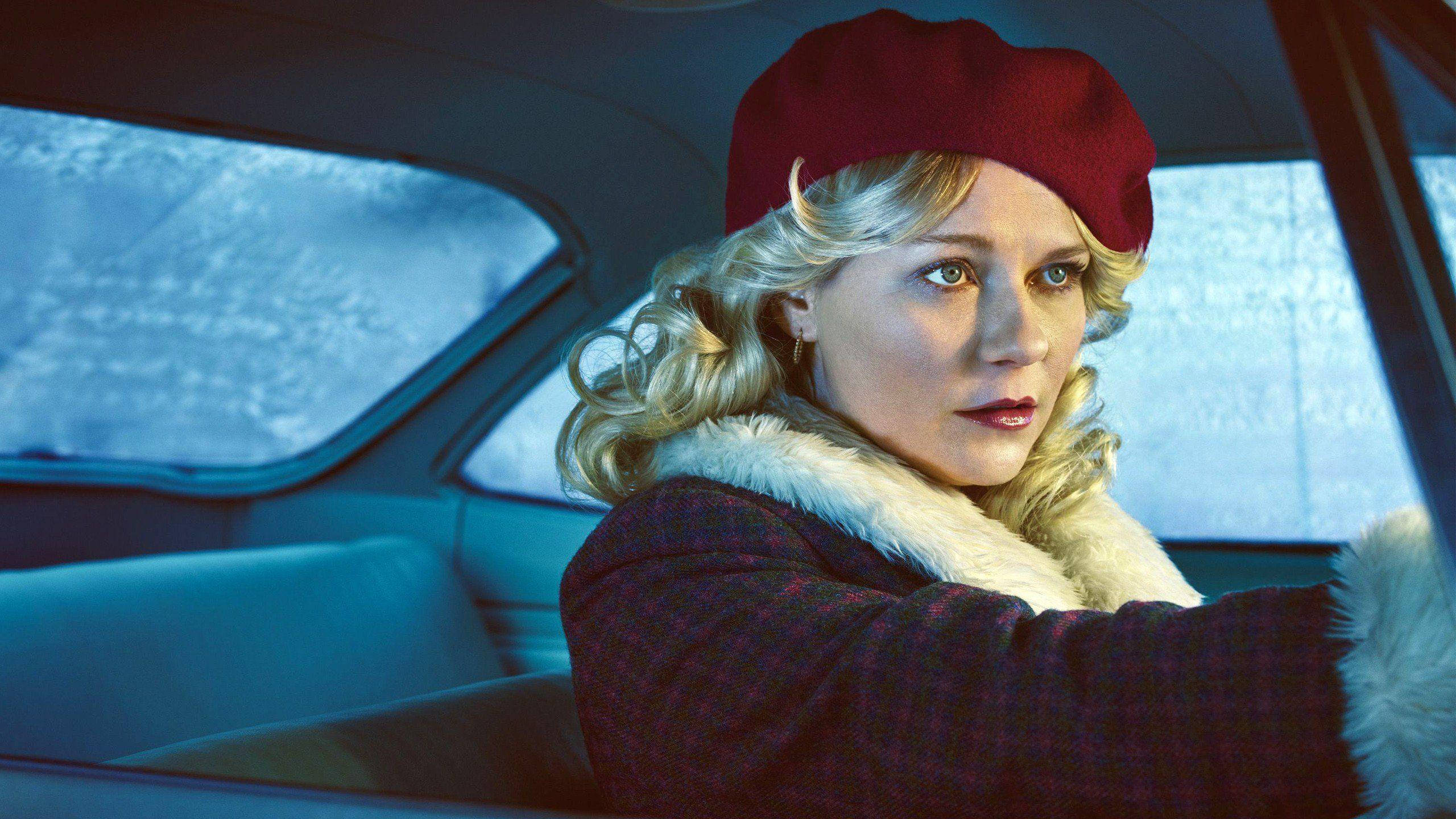 Kirsten Dunst 桌布 壁紙 — 一位金髮女子戴著紅色貝雷帽，身穿毛邊大衣，從一輛窗戶結霜的復古車內凝視著。