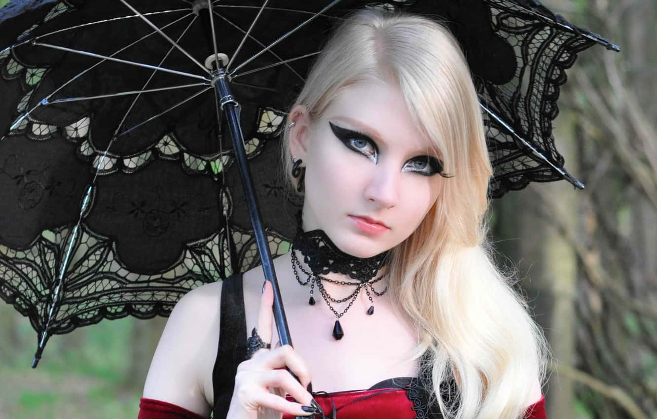 Gothic Fashion 桌布 壁紙 — 一位金髮女子畫著戲劇性的黑色眼線，手持一把黑色蕾絲陽傘，背景是模糊的森林。