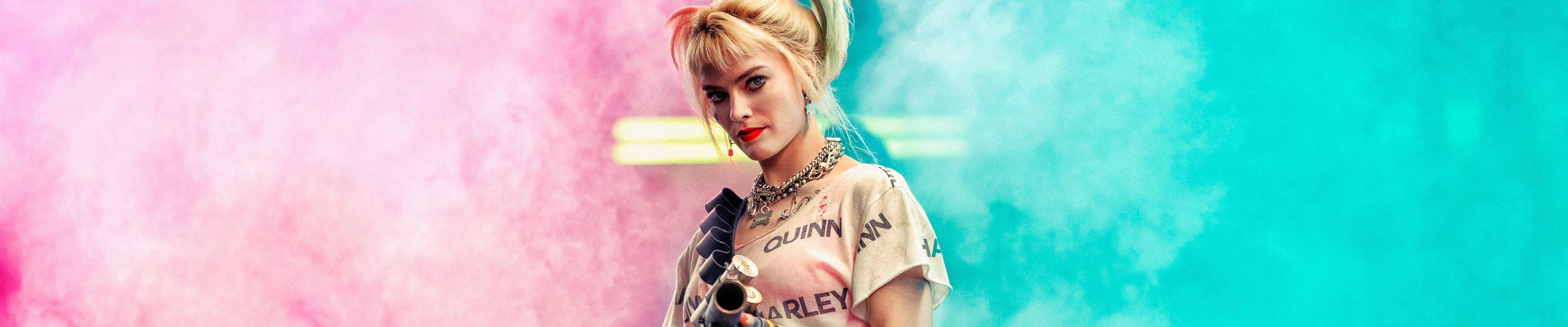 哈莉·奎茵 桌布 壁紙 — 一位金髮女子穿著 Harley Quinn T 恤，站在充滿活力的粉紅色和藍綠色煙霧背景前。