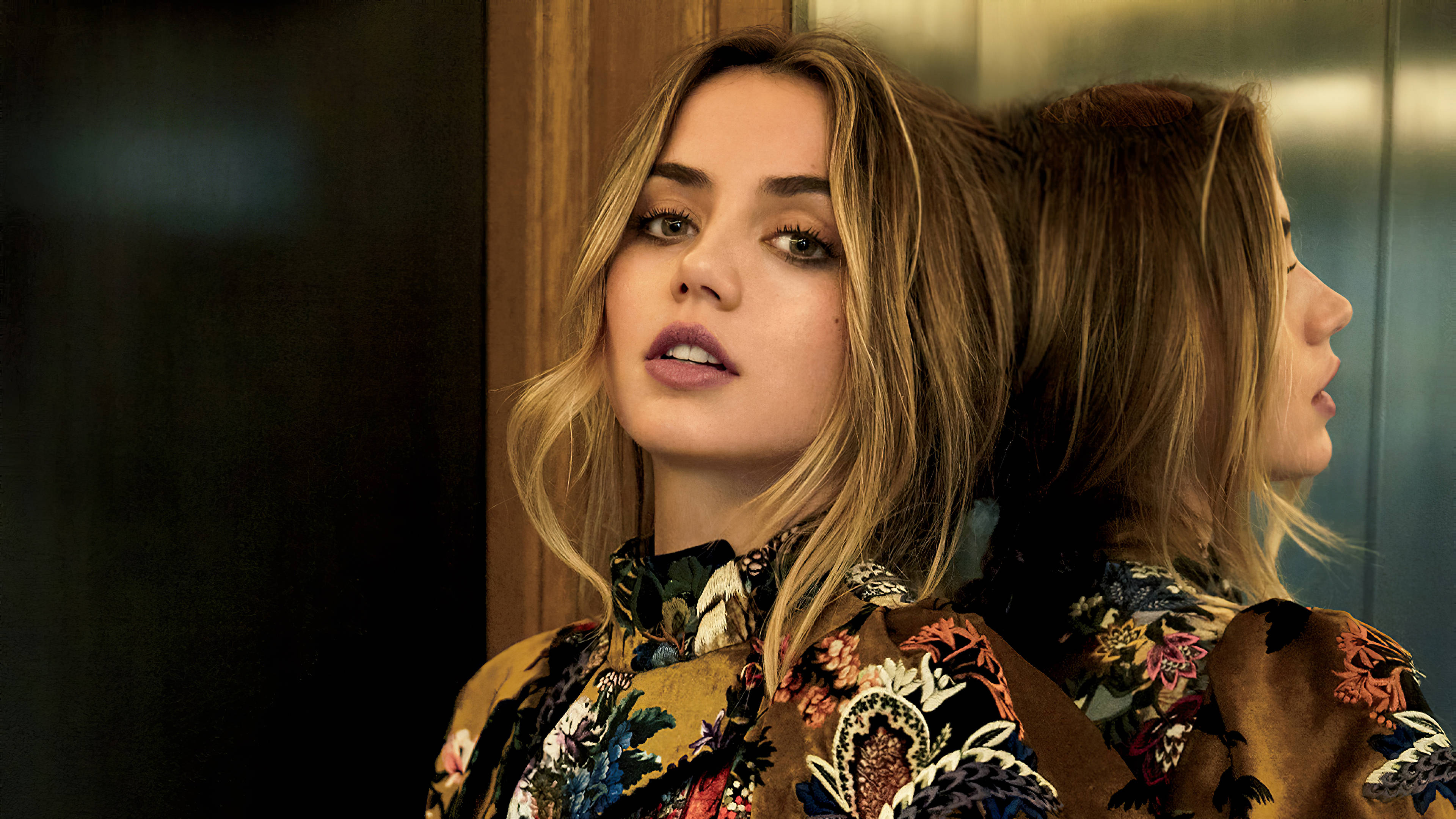 ana de armas 桌布 壁紙 — 一位金髮女子穿著花卉圖案襯衫，凝視前方，她的倒影出現在旁邊的鏡子中。