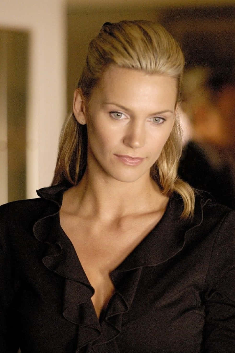 Natasha Henstridge 桌布 壁紙 — 一位金髮女子穿著黑色荷葉邊襯衫，表情嚴肅的特寫肖像。