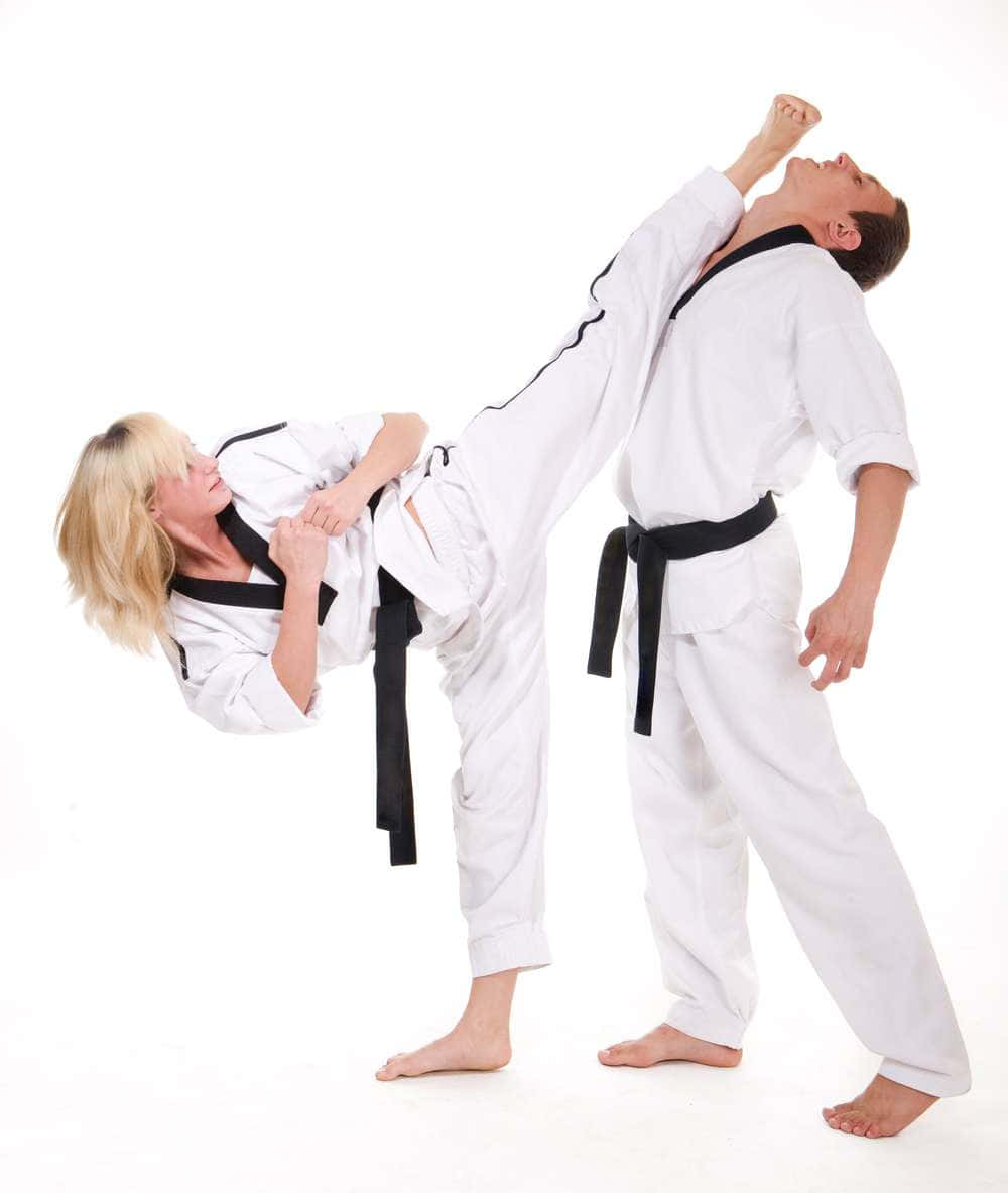 Martial Arts Uniform 桌布 壁紙 — 一位金髮女子身穿白色空手道道服，在純白背景前向一名身穿白色道服的男子施展高踢腿。