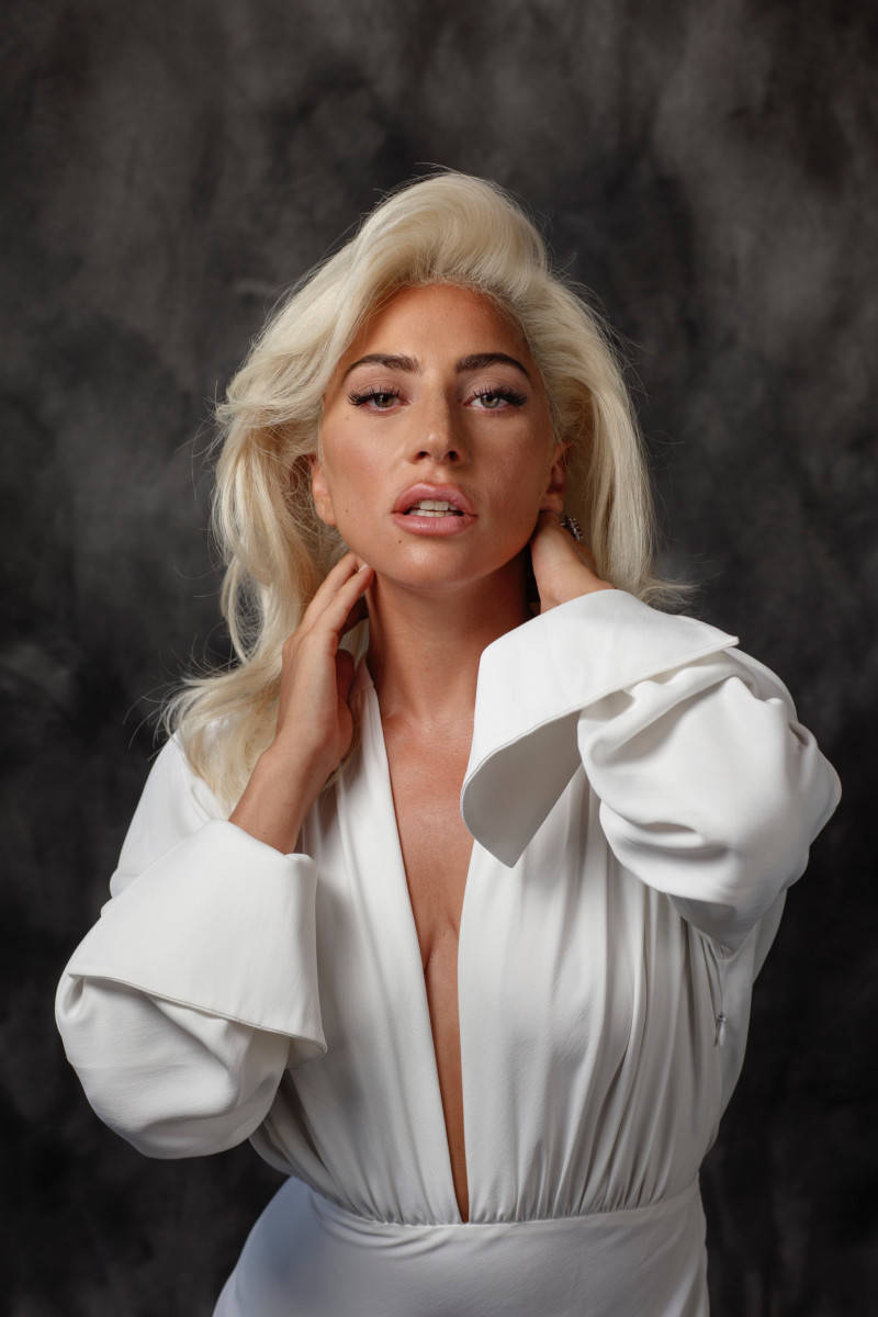 Celebrity 桌布 壁紙 — 一位金髮女子身穿白色襯衫，雙手放在脖子上，在深色紋理背景前擺姿勢。