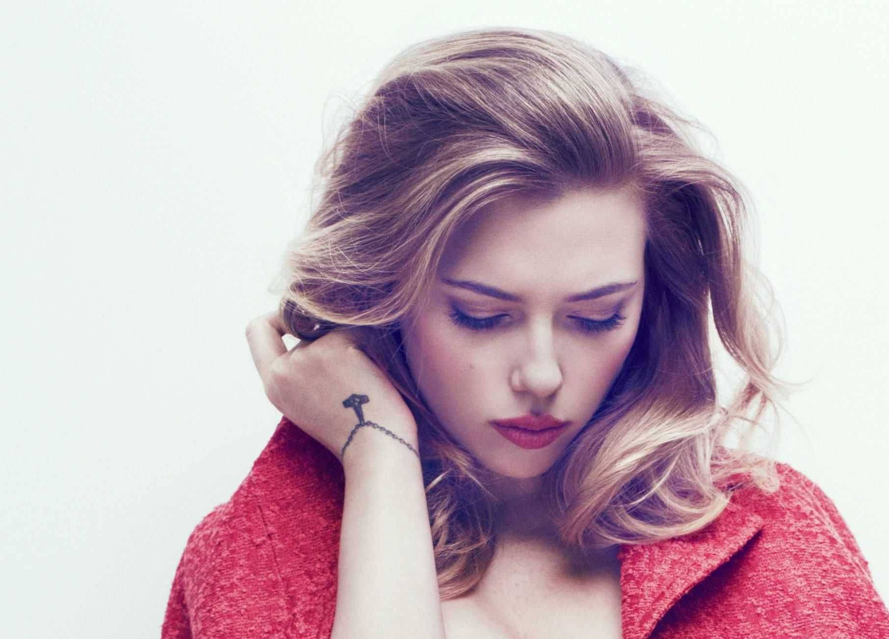 Scarlett 桌布 壁紙 — 一位金髮女子身穿紅色外套，在純白背景前低頭沉思。