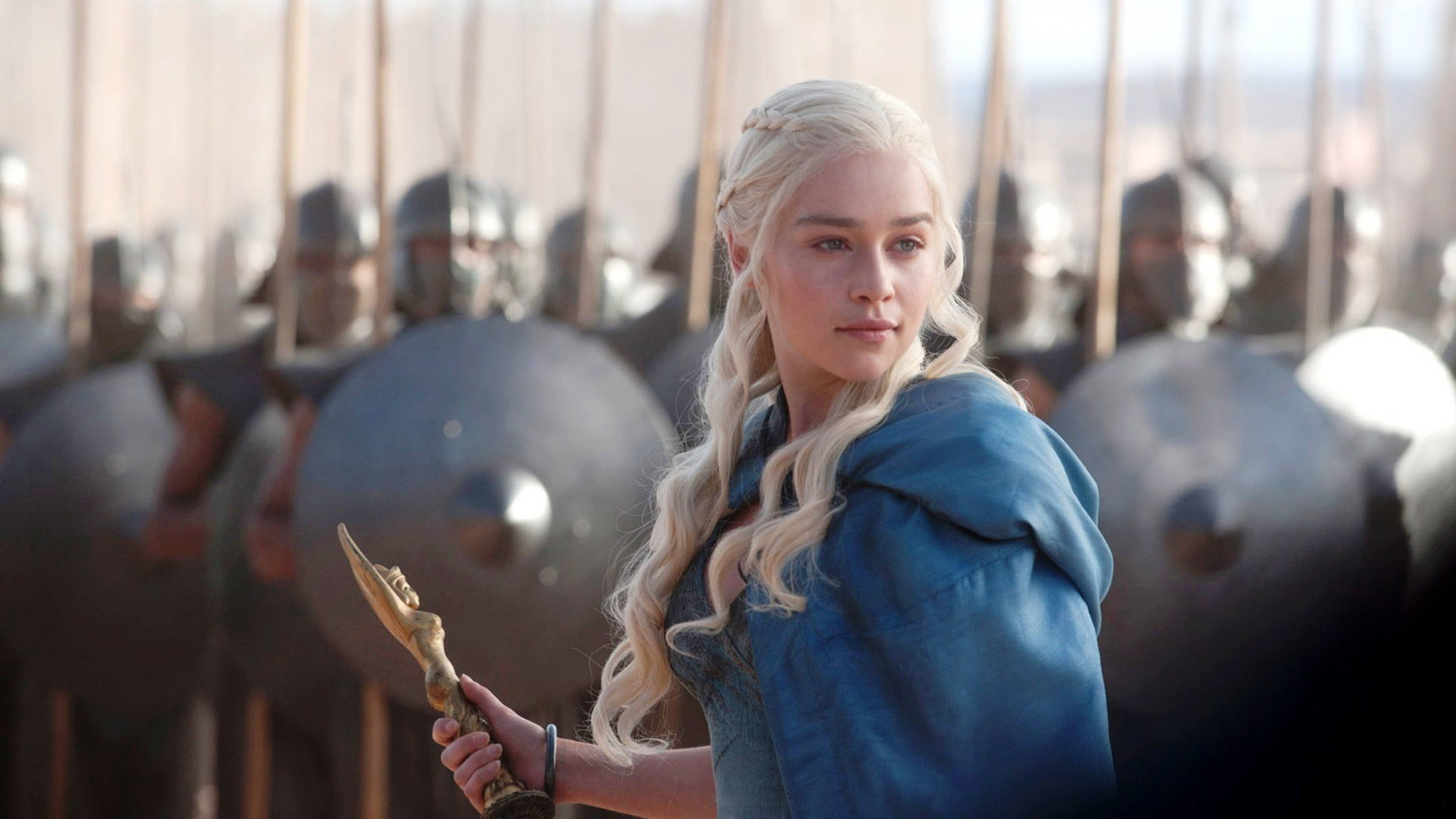 daenerys 桌布 壁紙 — 一位金髮女子身穿藍色斗篷，手持金色權杖，站在一排手持盾牌的裝甲士兵面前。