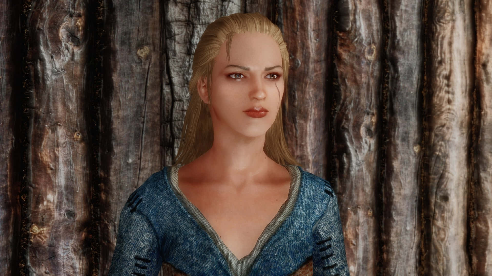 Skyrim Delphine 桌布 壁紙 — 一位金髮女子身穿藍色質感上衣，站在一面帶有風化紋理的鄉村風格木牆前。