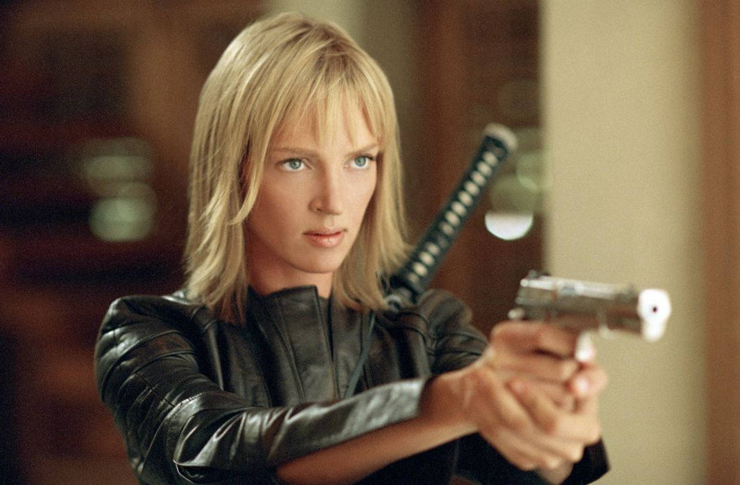 Kill Bill 桌布 壁紙 — 一位金髮女子身穿黑色皮夾克，專注地瞄準手槍，同時一把武士刀擱在她肩上。