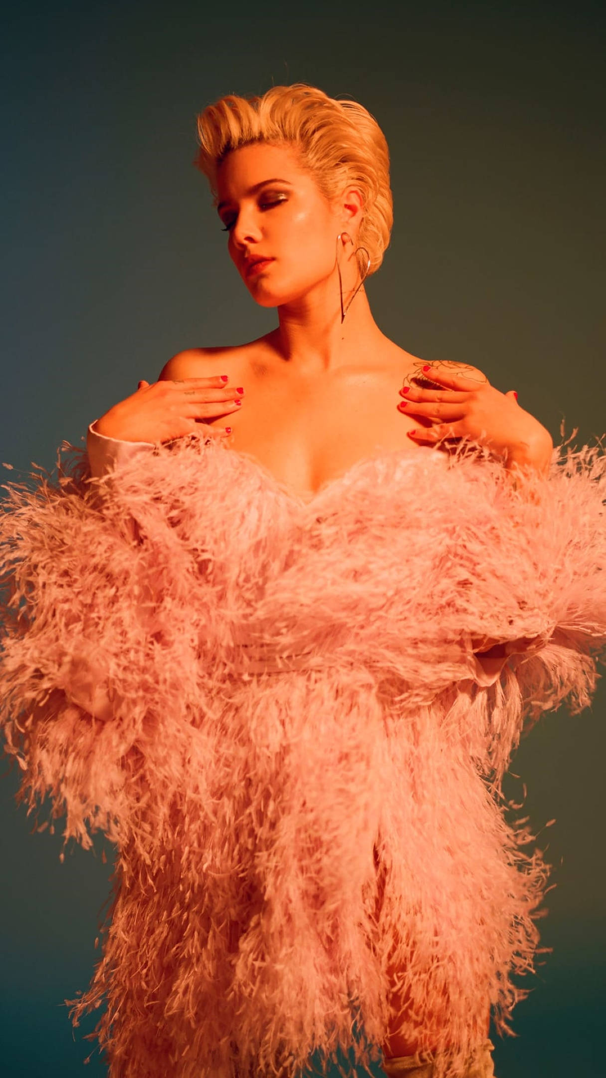 Halsey 桌布 壁紙 — 一位金髮女性穿著一件蓬鬆的粉紅色羽毛連衣裙，在溫暖的燈光下以藍綠色背景為襯托。