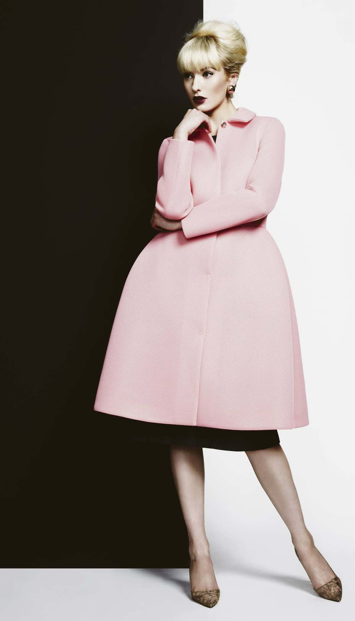Pink Coat 桌布 壁紙 — 一位金髮女性穿著復古粉色外套，在強烈的黑白背景前擺姿勢，光線效果戲劇化。