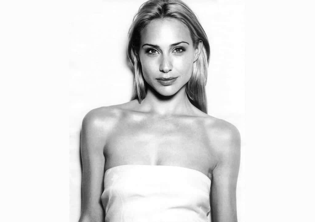 Claire Forlani 桌布 壁紙 — 一位金髮女性穿著白色無肩帶上衣，在素色背景前的黑白肖像。