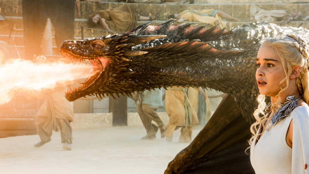 dracarys 桌布 壁紙 — 一位金髮女性站在一個巨大的黑色噴火龍旁邊，背景是陽光普照的石頭庭院，有模糊的人影。