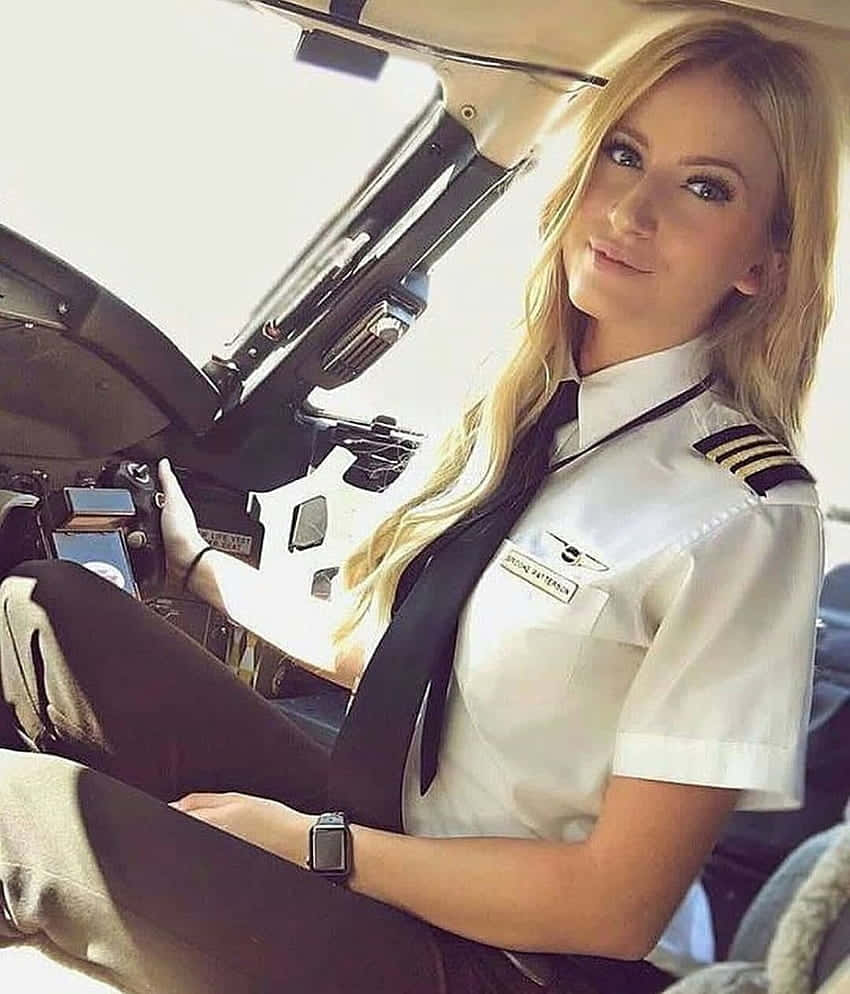 Plane 桌布 壁紙 — 一位金髮女飛行員穿著制服，在陽光照射的明亮駕駛艙內自信地微笑。